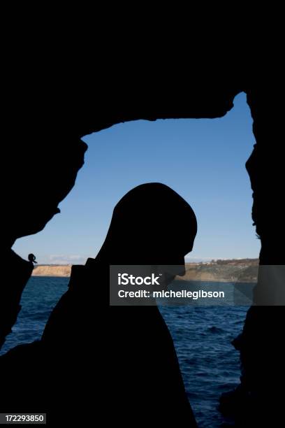 Photo libre de droit de Silhouette Dun Homme Debout Dans Une Grotte Ouverture Sur Le Lac banque d'images et plus d'images libres de droit de Abstrait