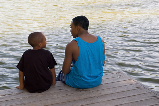 Brothers talking on pier at dusk, 7 and 15 yrs old.
