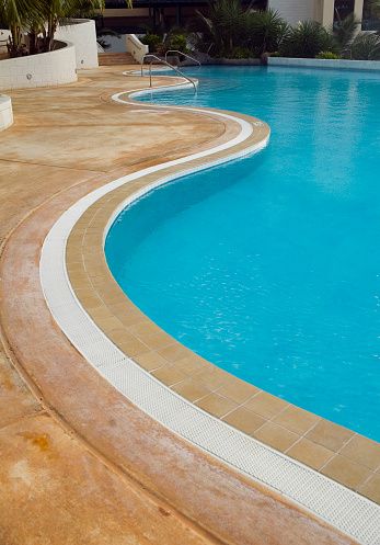 Low angle on curved edge of a luxury resort swimming pool.