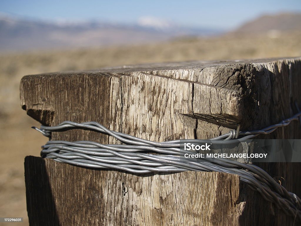 Western Ranch Barbed Wire Detail - Cowboy Valley Detail of barbed wire fencing post.  Open range ranching wiht snow capped mountains and valley in the background. Barbed Wire Stock Photo