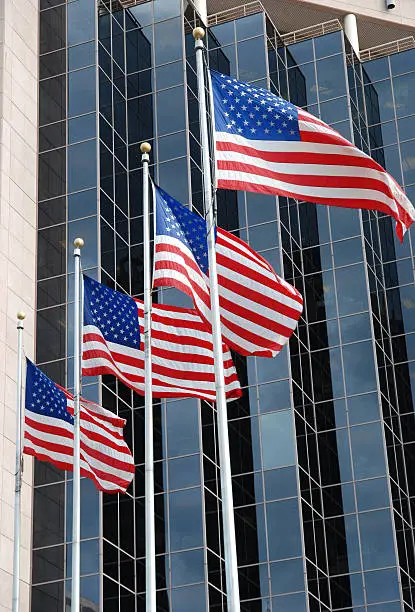 four flags waving over modern office building