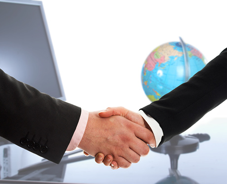 Focus on businesspeople handshake with monitor and earth globe in background