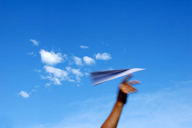 A paper plane soaring through the sky stock photo