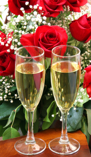 Two champagne flutes in front of beautiful roses