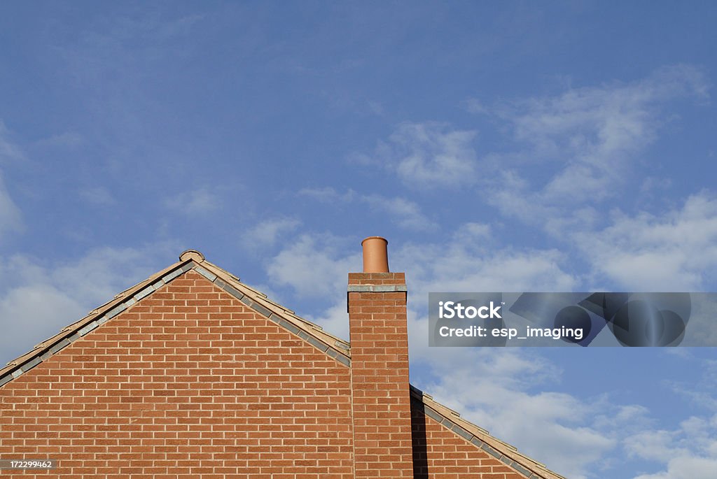 Gable end of Modern House "Gable end of a modern brick house, with chimney and blue sky behind. Space for copy." Gable Stock Photo