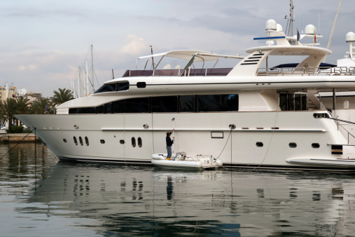 An operator cleans this for sale impressive yatch in the Palma de Mallorca Harbour. An operator cleans an impressive yacht for sale in the Marina of Palma de Mallorca before the summer season.