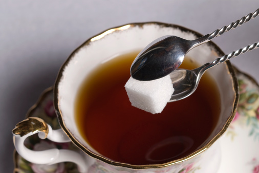 Sugar Cube in Silver Tongs over Tea Cup