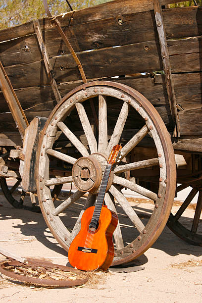 Old covered wagon and one of its wheels with a antique classical guitar leaning next to it for the perfect Country and Western music look