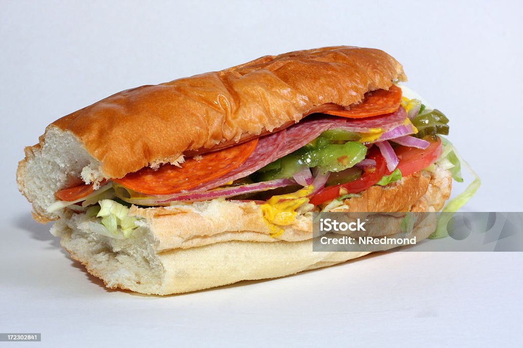 Deli-style sandwich A sub sandwich with ham, salami, bologna, lettuce, tomato, pickle and onion with a smear of mustard. American Culture Stock Photo