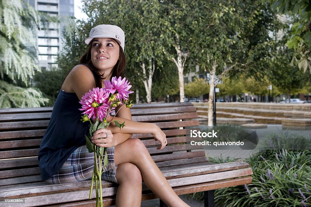 Beautiful Latina Young Woman Suprised with Flowers on Bench, Copyspace "Young Latina woman sitting on park bench holding bunch of flowers, looking up. Copy space. CLICK FOR SIMILAR IMAGES AND LIGHTBOX WITH BEAUTIFUL WOMEN." Girlfriend Stock Photo