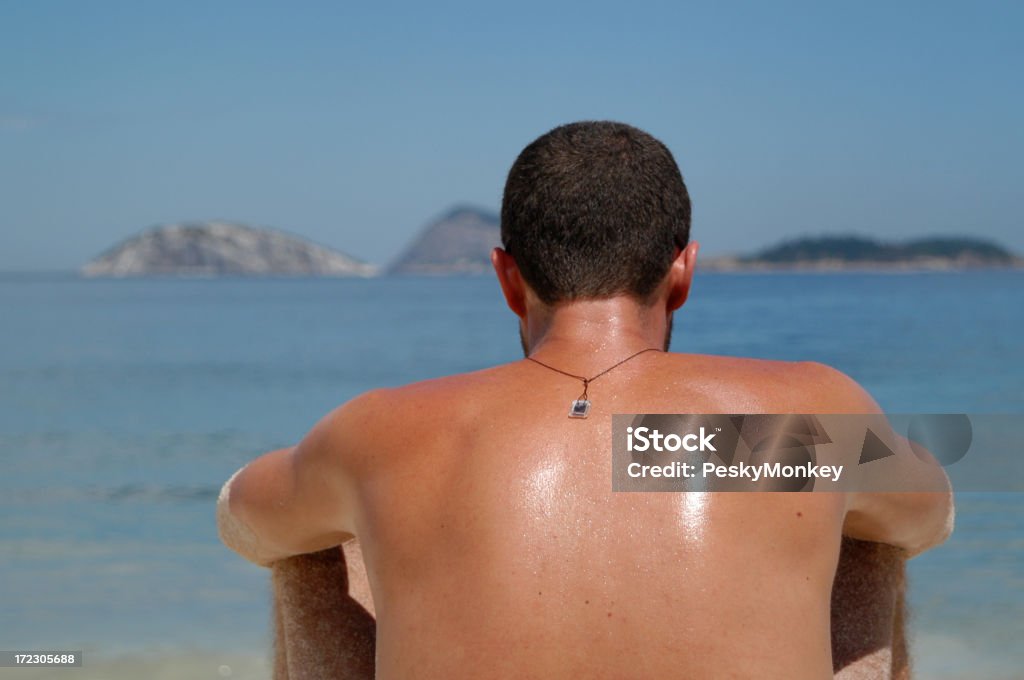 Brazilian Man Sunbathing on Ipanema Beach Rio de Janeiro Brown Brazilian back looking out at the islands from Ipanema Beach in Rio de Janeiro Sweat Stock Photo