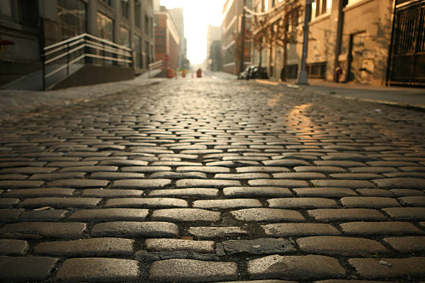 Deserted Brooklyn DUMBO Cobblestone Street Morning Cobblestone street in old Brooklyn near the waterfront district of DUMBO at dawn. Close focus on near cobblestones. dumbo new york photos stock pictures, royalty-free photos & images