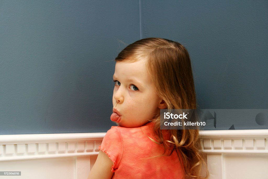 Girl standing in corner with tongue stuck out for time out Naughty child stands in the corner Child Stock Photo