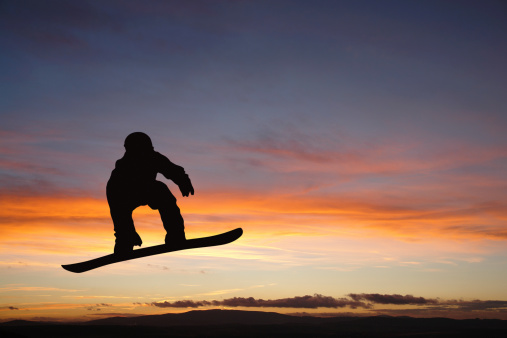 Silhouette of jumping man on snowboard