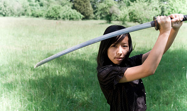 istock Young Ninja Girl In Field with Drawn Katana Sword 172307093