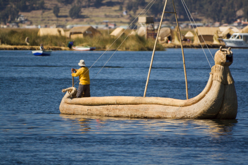 Subject: Rowing the reed boat on Lake Titicaca, with the indigenous villages of the floating islands in the background