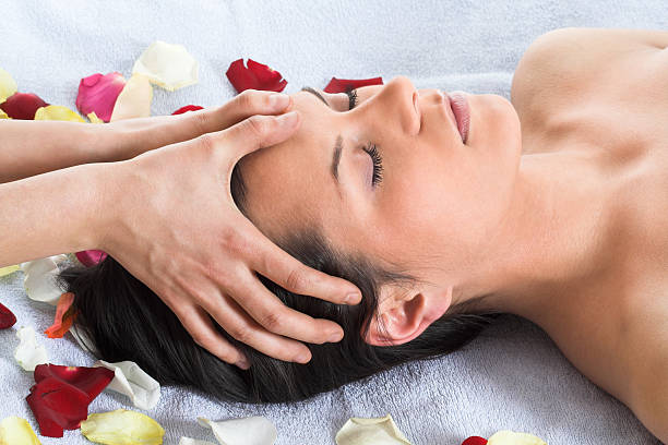 Brunette getting a head massage laying on a white towel stock photo