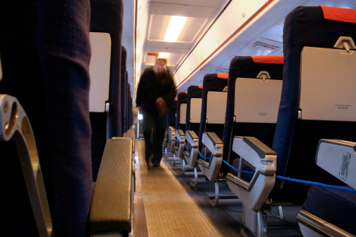 A motion blurred figure walks up the aisle of an empty aircraft