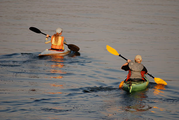 Twilight Kayak Paddlers, Great Slave Lake, Northwest Territories. Two paddlers play in their kayaks on Great Slave Lake, Yellowknife Bay, Northwest Territories.  The lake is calm and it is twilight time. great slave lake stock pictures, royalty-free photos & images