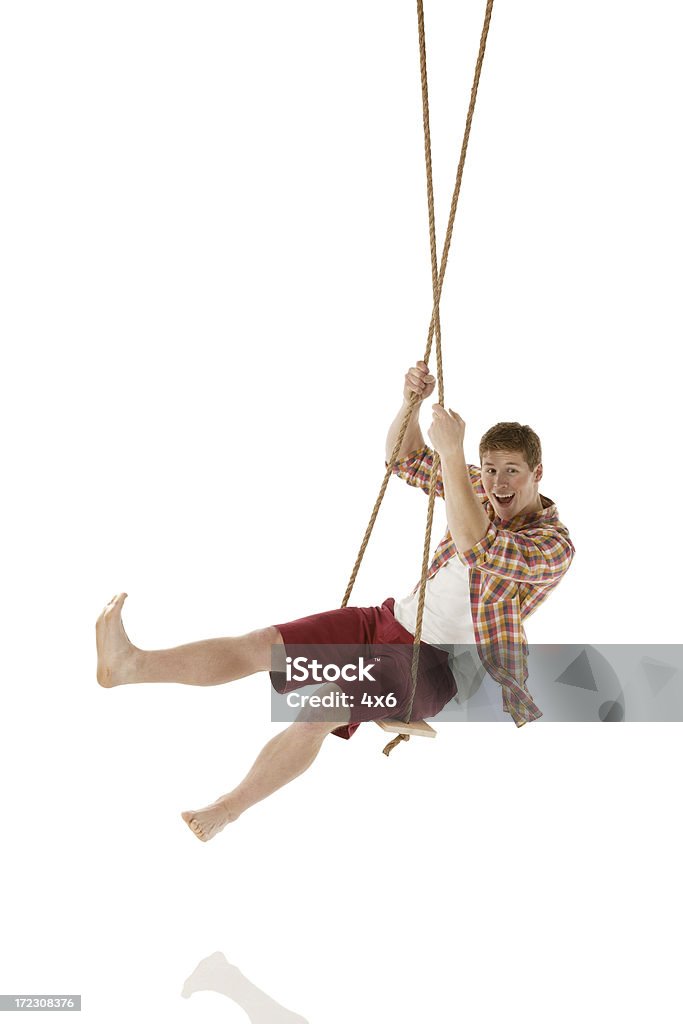 Happy young man balanceo en un columpio de cuerda - Foto de stock de 20 a 29 años libre de derechos