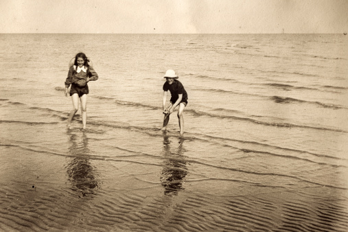 Vintage photograph of a young girl and boy playing in the sea.  From the late victorian or early edwardian period.