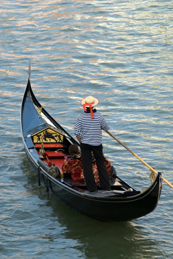 A Venetian Gondolier with clients in his boat.