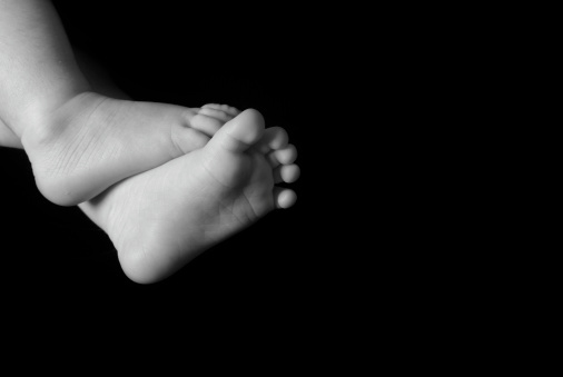 Newborn baby feet with chamomile. Nature background.