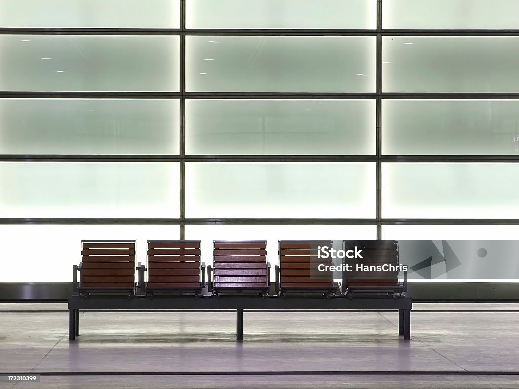 Bench A bench with 5 seats in a train station with lighted walls in background. Spot light at the 3rd seat (middle). Bench Stock Photo