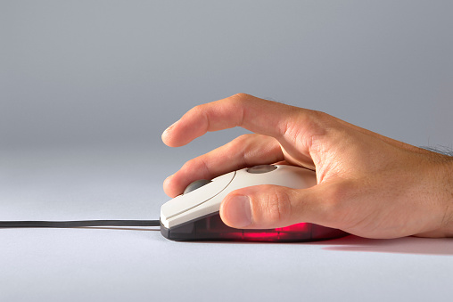 Man's hand is holding in hand optical mouse with scroll and red back-light, studio shot.