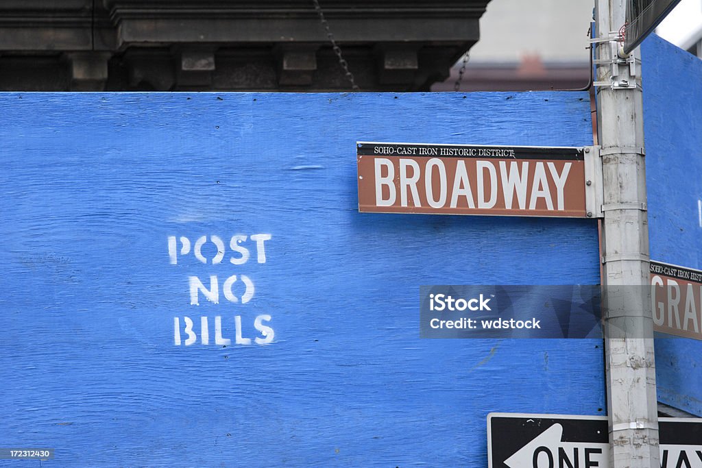 Broadway Sign Against POST NO BILLS A Broadway street sign over a POST NO BILLS painted plywood board in Soho New York City. SoHo - New York Stock Photo