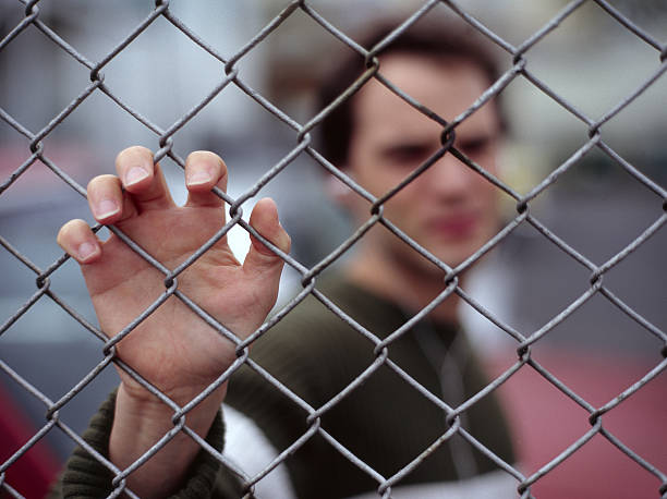 A man stuck behind a chain link fence.