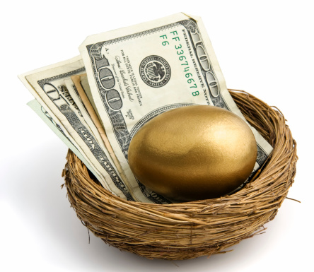 Gold egg sitting atop a stack of bills with a one hundred dollar bill on top.  Shot on white. Part of series.