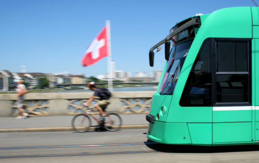 Modern Street Car in Basel, Switzerland, with motion blur. In the background you can see the Swiss National Flag and the Rhine River.