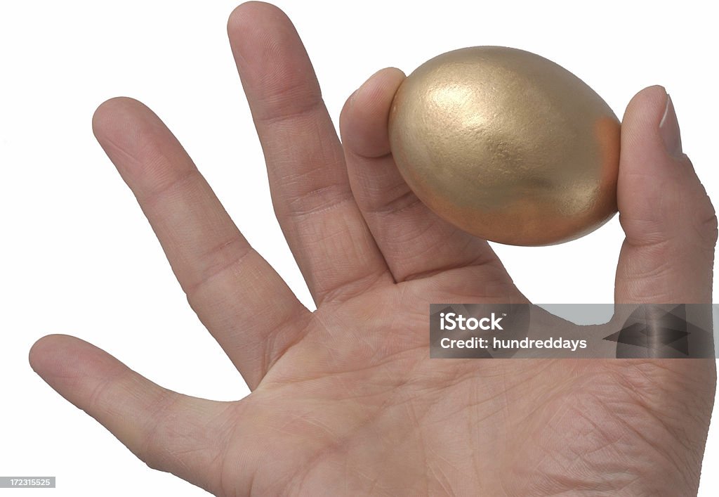 Mano con uovo d'oro - Foto stock royalty-free di Scontornabile