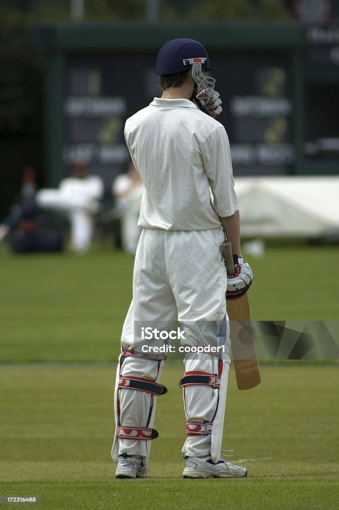 Batsman ready to play cricket A batsman standing in the middle of the wicket with the scoreboard in the background Sport of Cricket Stock Photo