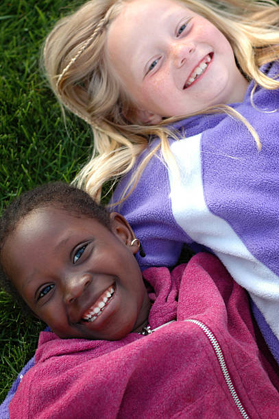 istock Two Happy Girls Smiling and Lying in the Grass 172316510