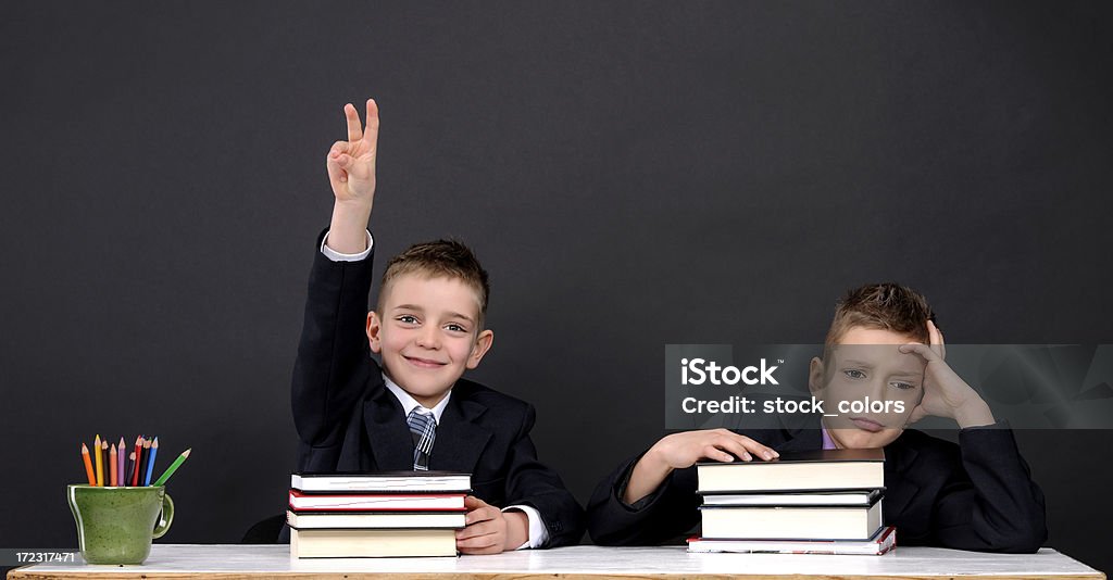 school boys two school boys with arm raised, one is bored. 10-11 Years Stock Photo