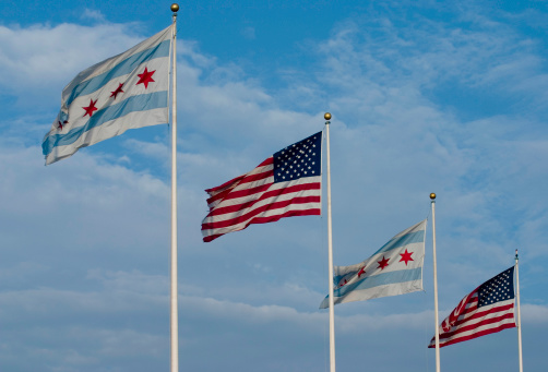 alternating line of City of Chicago flags with USA flags against a blue sky