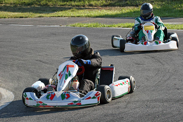Two people with helmets racing go-carts around a track Into the curve at high speed. go carting stock pictures, royalty-free photos & images