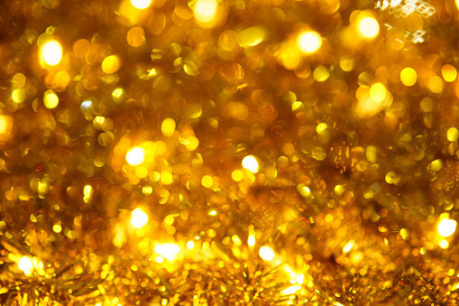 Christmas glowing golden background. Christmas lights. Golden Holiday New Year Abstract Glitter Defocused Background with Flashing Stars and Sparks. Blurred Bokeh.