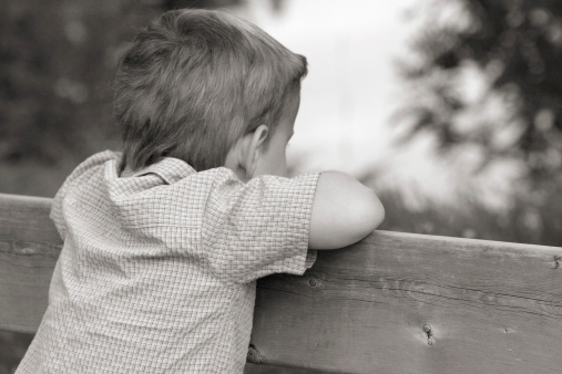 A little girl sneeks a peek through a fence.