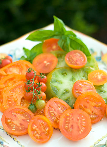 地元の野菜と食材、バジル&オレンジ色のエアルームトマトサラダ - heirloom tomato homegrown produce tomato organic ストックフォトと画像