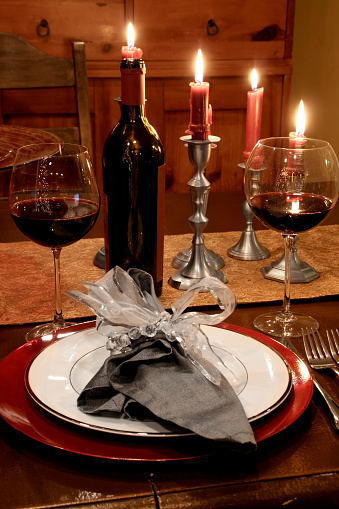 Dinner by candle light. Red wine, candles and a table setting.