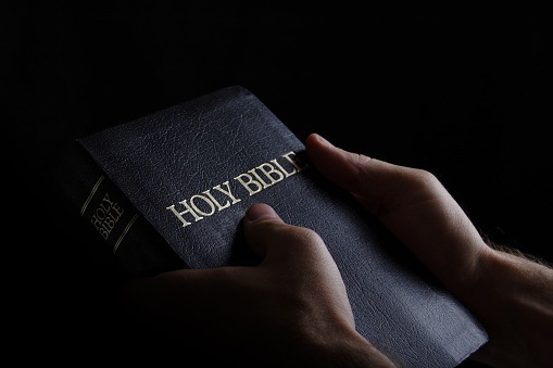 Male hands holding a Bible.