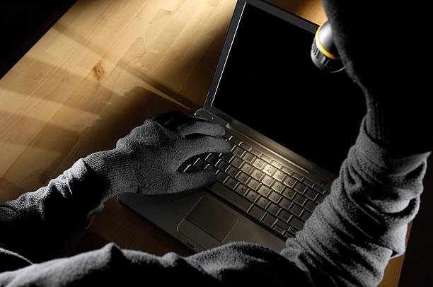 istock Intruder Examining Laptop With Torch 172322130