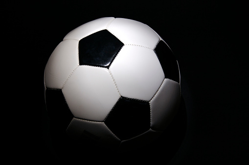 Spotlit soccer ball on black.