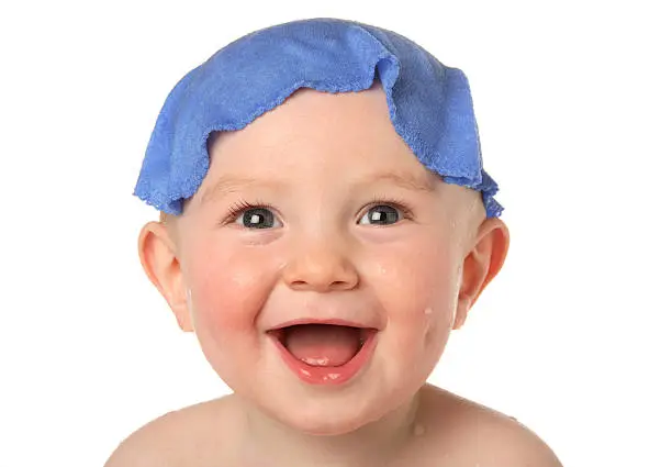 Little baby boy having fun at bathtime with face cloth on head.