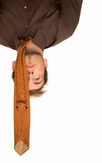 Buisnessman is hanging upside down, isolated on white.