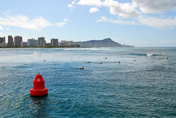 Buoy Surfers Early morning surfers at Waikiki Beach with Diamond Head in the background channel marker stock pictures, royalty-free photos & images