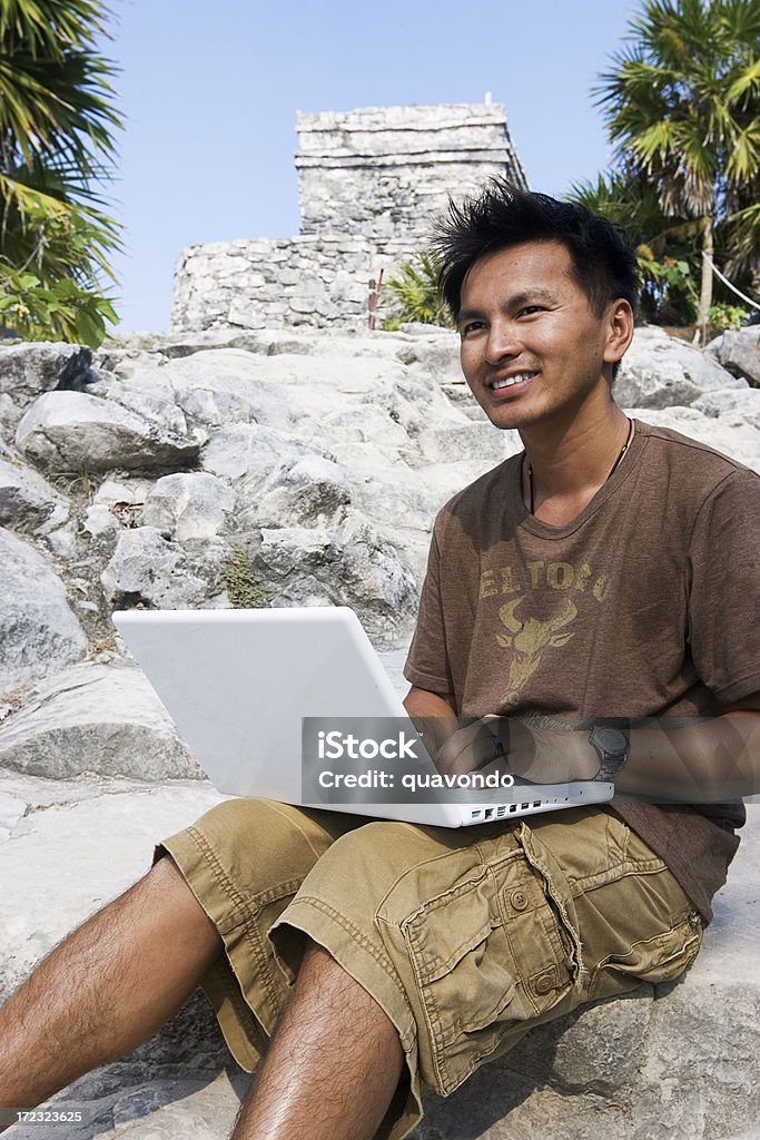 Hombre joven asiático utilizando el ordenador portátil al aire libre en México ruinas, Copyspace - Foto de stock de 20 a 29 años libre de derechos